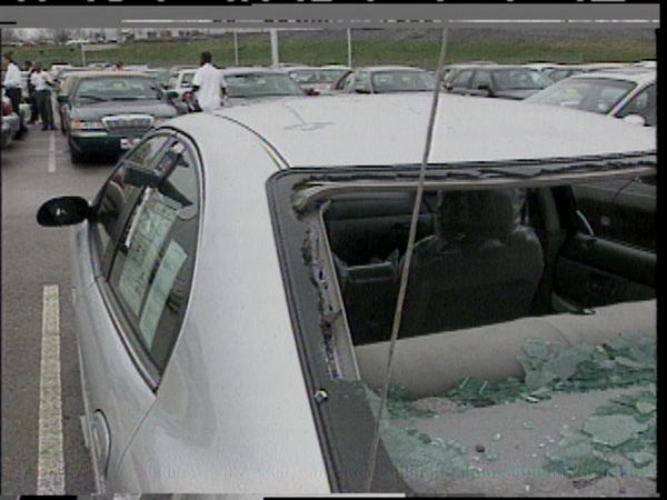 A silver car with its rear window smashed and the roof dented by hail in Missouri