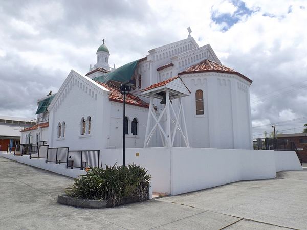 A white church with blue tarps covering its hail-damaged roof