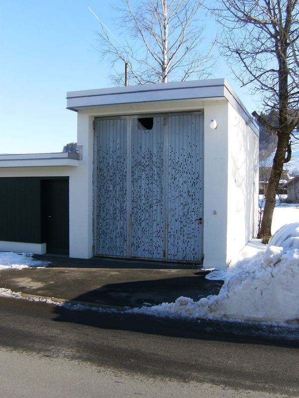 A white rendered wall covered in small dark pockmarks from hail impacts