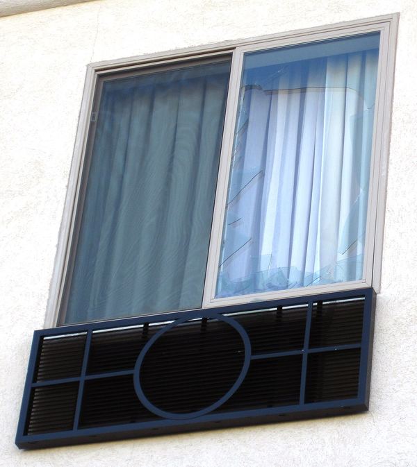 A second-floor motel window with a shattered pane after a hailstorm