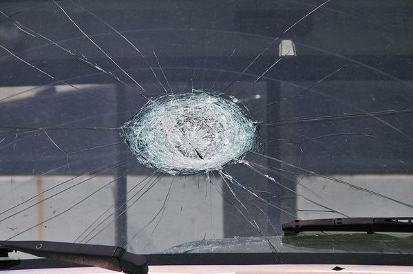 A truck windshield with a large starburst crack from a baseball-size hailstone